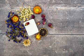 Obraz na płótnie Canvas Dried flower head arrangement with white patchouli soap bar on wooden planked rustic background
