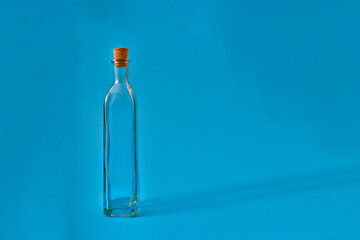 Empty glass bottle with original shapes on a solid neutral colored background.
