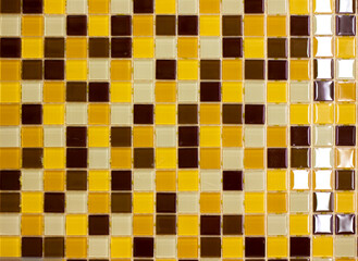 mosaic of small ceramic blocks of yellow, brown and beige color for wall design in the interior close-up background