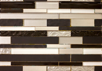 wall of small ceramic tiles, horizontal long bars of black, white and pearl color background...