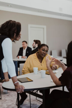 Female Entrepreneurs Discussing While Male Colleagues In Background At Corporate Office