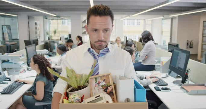 Businessman getting fired carrying box of personal belongings being made redundant in recession sad worried failure