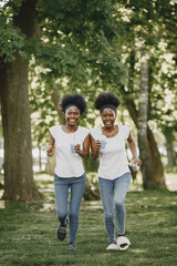 Fototapeta premium Twin sisters holding a cups with drinks and running on a camera