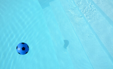  a child's yellow balloon inside the blue water of a swimming pool among the reflections of the...