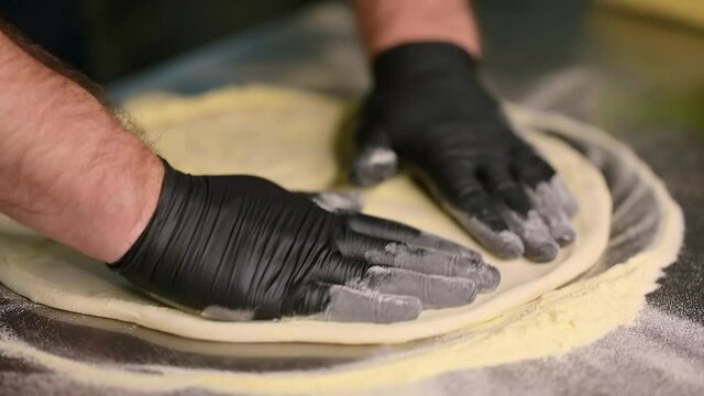 Preparation of pizza dough. Chefs in protective gloves preparing pizza in the kitchen of restaurant