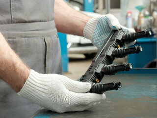A new induction coil for the car engine. The car mechanic holds in his hands, examines the...