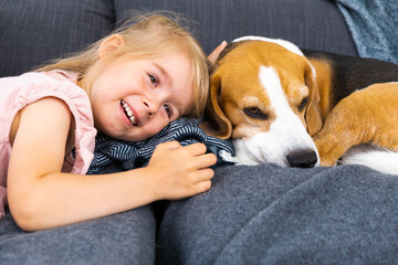 Happy Child with beagle dog lying on couch. Kids with dogs concept