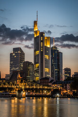 Obraz premium Illuminated high-rise buildings on the banks of the Main in Frankfurt after sunset, vertical