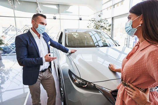 Professional Salesman Consulting His Client In Car Showroom