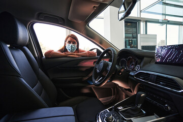Young woman looking at the new car from the inside
