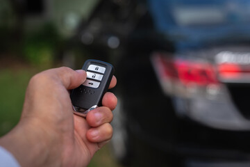 Hand of a man holding and push remote control of black car, technology transportation safety concept