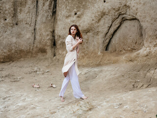 pretty woman posing near rocks in the sand attractive look