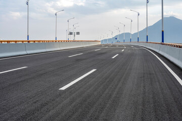 Empty asphalt highway road with city skyline.