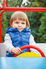 Fototapeta na wymiar Little baby boy playing with toy car on playground in park. Child development concept