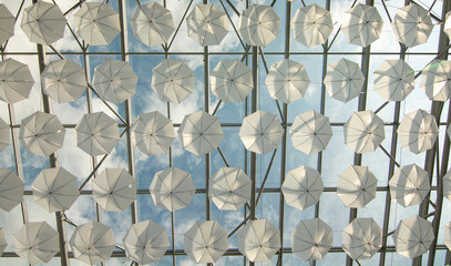 White umbrellas hanging from the ceiling in the shopping mall. Background. Texture. Abstract.