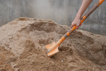 pile of sand, hand of a construction worker scooping sand for mix mortar on construction site,...