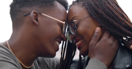 Close up portrait of happy young afro couple in love kissing sitting on bench outdoors