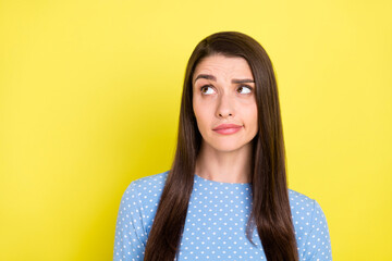 Photo of doubtful unsure young lady wear dotted outfit looking empty space isolated yellow color...