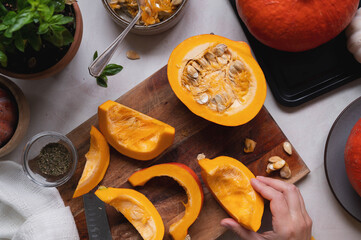 Fresh pumpkin. Cutting pumpkin in slices on cutting board, female hands preparring autumn foods. Baked squash or butternut.