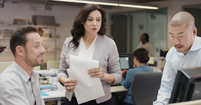 Woman Manager Leading Diverse Team Meeting In Small Business. Three People Working Around Computer Late At Night