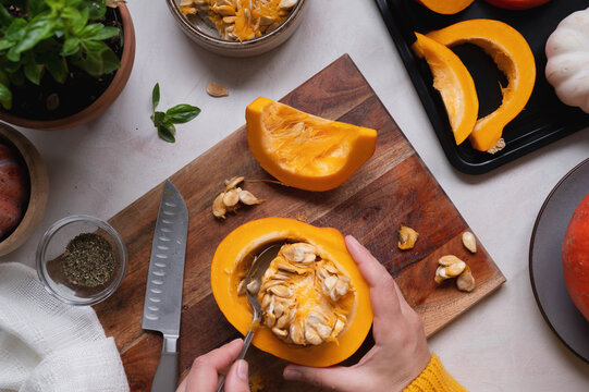 Cooking pumpkin food. Female hands taking off pumpking seeds. Top view of cooking a squash or butternut soup or pie.