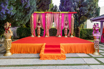 Decorated orange stage at a traditional Indian party in a park on a sunny day