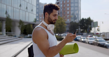 Side view of indian man using smartphone app after training outdoors