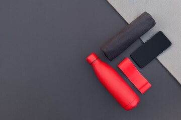 Sportive equipment of red color and phone on grey background and grey mat.