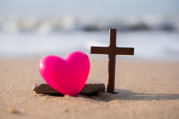 A wooden cross on the sand on the beach.
