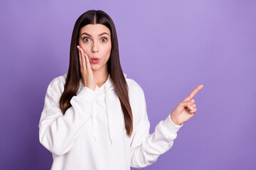 Photo of happy young positive woman look empty space shock hand cheek isolated on purple color background