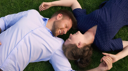 Top view of young couple lying on green grass outdoors