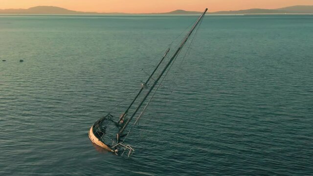 Aerial: Sunken yacht in the water at sunset. San Pablo Bay, Oakland, USA