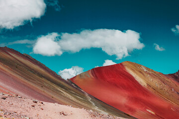 Mountains with vibrant and warm colours with a strong blue sky and clouds.