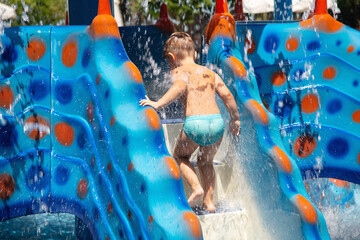 Boy climbs the water slide at aqua park . 