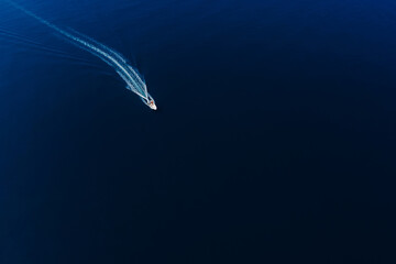 Motor boat is sailing in blue deep sea. Aerial view