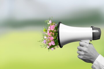 Megaphone with bouquet with blooming spring fresh flowers on pastel background.