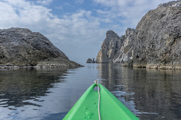 View from the nose of a green sea kayak that floats between the stones and mount Karaul-Oba on the sea. Crimea. Novy Svet