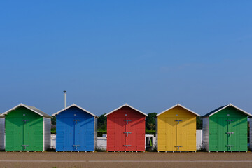 Multi-coloured beach huts in Eastbourne beneath a clear blue sky in the summer