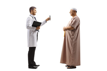 Full length profile shot of doctor holding a smartphone and showing screen to an arab man