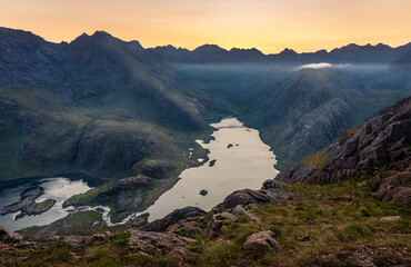 The sun setting behind the Black Cuillin Ridge with the remote Loch Coruisk in the glen below, Isle of Skye