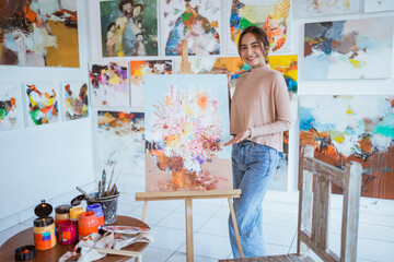 asian female painter painting on canvas in her workshop