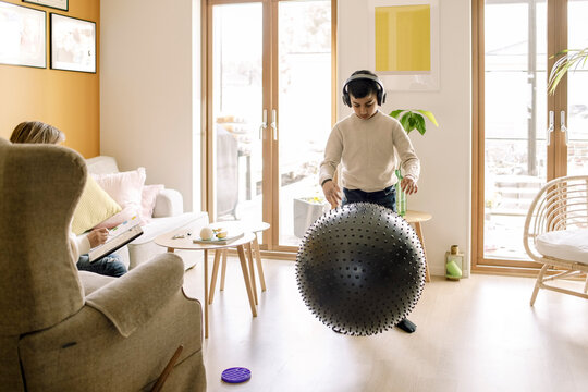 Pre-adolescent boy playing with fitness ball in living room
