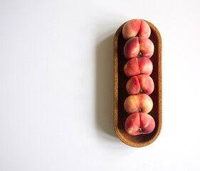 Fresh ripe six flat donut peaches, saturn peaches, in a cork tray. Isolated on white background,...