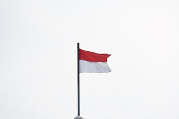 Flag of Indonesia, the Red and White (Merah Putih), flying from a standalone flagpole, in the afternoon, in daylight.