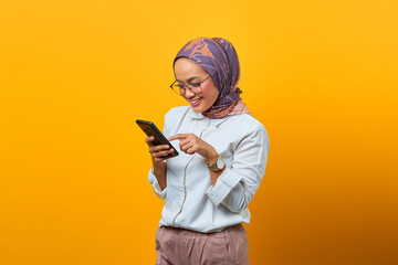 Portrait of beautiful Asian woman smiling using mobile phone over yellow background