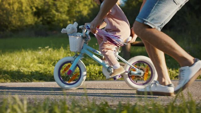 Side view of father teaching his daughter how to ride a bike.