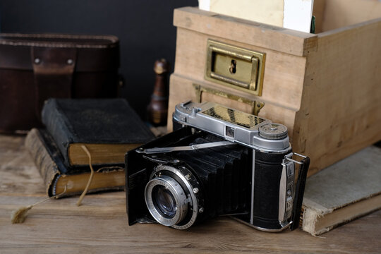 old family photos 50s, 40s, retro camera, books on wooden table, concept of genealogy, memory of ancestors, family tree, childhood memories, home archive