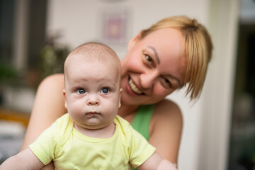 Mother enjoys holding her little cheerful baby boy.