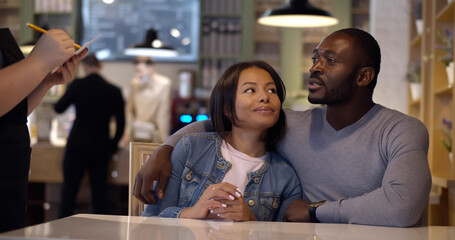 Happy afro-american couple on date making order in cafe