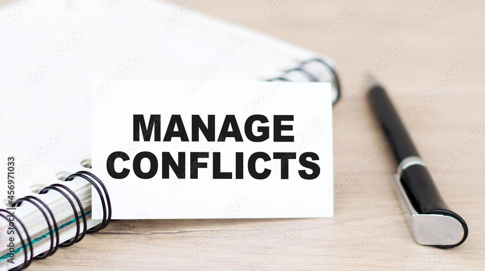 Aufkleber white card with the words manage conflicts on the table next to a pen and a notebook